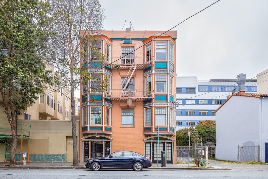 A black car is parked in front of a multi-story building.